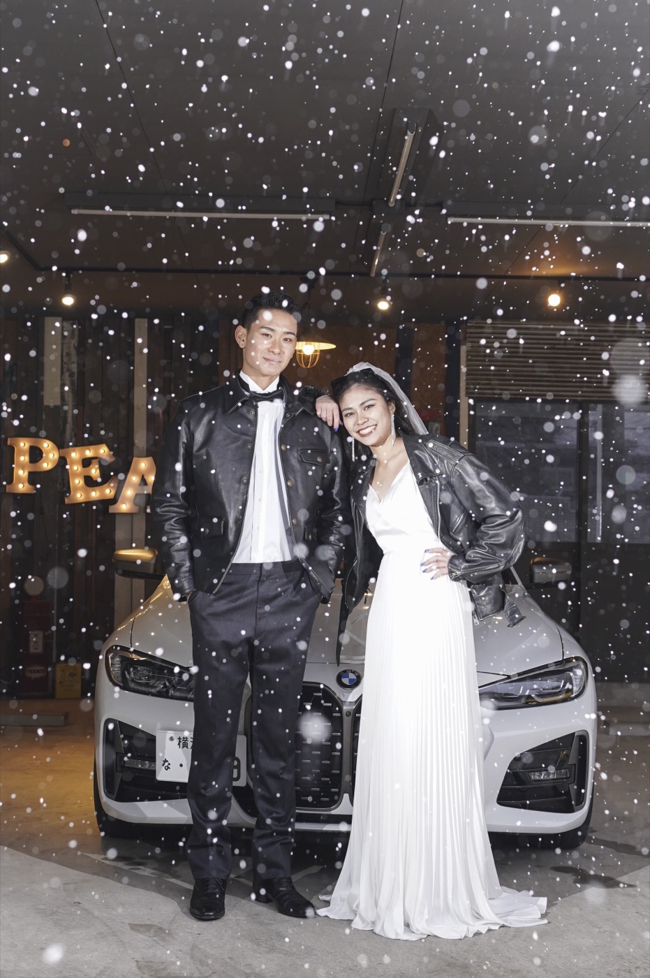 雪の降る夜、白いSUVを背景にした新郎新婦