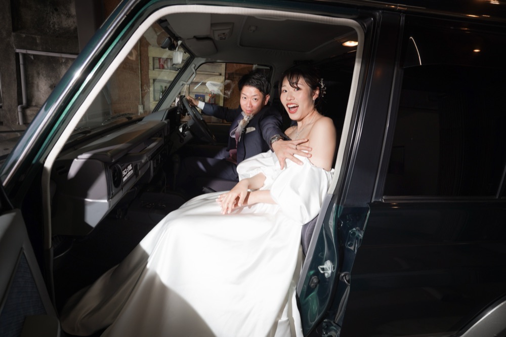 車内で笑い合う新郎新婦のウェディングフォト